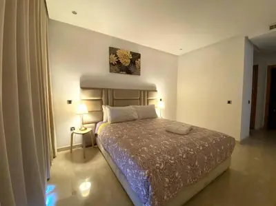 a bedroom with a bed and a table with a lamp at Maarif City Sunrise- 3 Beds - By AppartAli in Casablanca