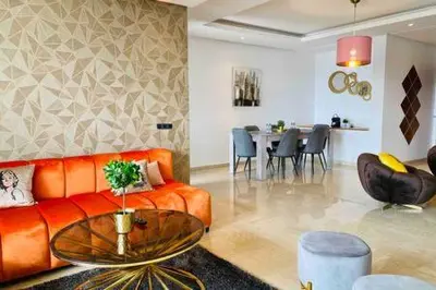 a living room with a orange couch and a table at Maarif Sunset View - 3 Bedrooms - By AppartAli in Casablanca