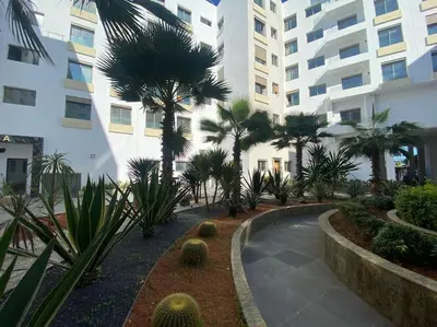 a courtyard with palm trees in front of a building at Corniche Casablanca - Red’s Neuf in Casablanca