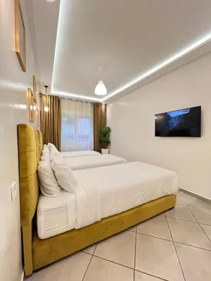 a bedroom with two beds and a tv on the wall at SUITOUISS - Océan 1 - Appartement centre ville au front de mer in Rabat
