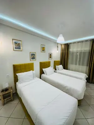 two beds in a hotel room with white sheets at SUITOUISS - Océan 1 - Appartement centre ville au front de mer in Rabat