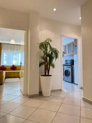 a living room with a plant in a large pot at SUITOUISS - Océan 1 - Appartement centre ville au front de mer in Rabat