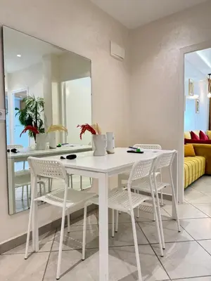 a white dining room table with white chairs and a mirror at SUITOUISS - Océan 1 - Appartement centre ville au front de mer in Rabat