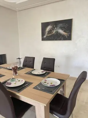 a dining room table with chairs and a wooden table with plates at Chic & cosy Flat Near Airport lockbox fast wifi in Nouaceur