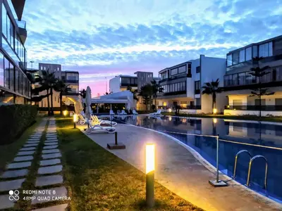 a swimming pool with a light next to some buildings at Grand Apartement a Blanca Beach Sidi Rehal in Sidi Rahal