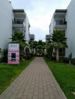 a brick walkway in front of a building with palm trees at Grand Apartement a Blanca Beach Sidi Rehal in Sidi Rahal