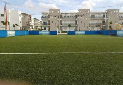 an empty soccer field with buildings in the background at Grand Apartement a Blanca Beach Sidi Rehal in Sidi Rahal
