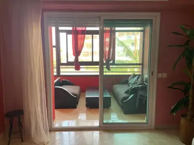 a living room with a sliding glass door with a couch at Appartement au bord de l'eau in Mohammedia