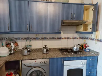 a kitchen with blue cabinets and a washing machine at Appartement au bord de l'eau in Mohammedia