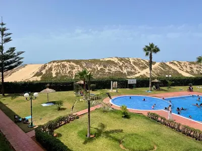 a swimming pool in a park with a mountain in the background at Appartement au bord de l'eau in Mohammedia