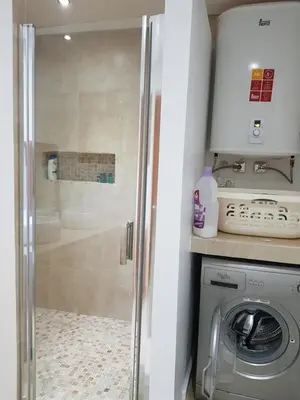 a shower in a bathroom with a washing machine at Les Portes de l'Océan avec piscine uniquement l'été in El Harhoura