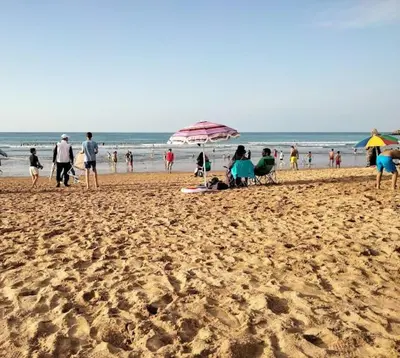 a group of people on a beach with an umbrella at Havre de Paix chez Lamine in El Harhoura
