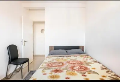 a bedroom with a bed and a black chair at Havre de Paix chez Lamine in El Harhoura