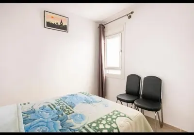 a bedroom with two chairs and a bed and a window at Havre de Paix chez Lamine in El Harhoura