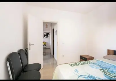 a white bedroom with a bed and a chair at Havre de Paix chez Lamine in El Harhoura