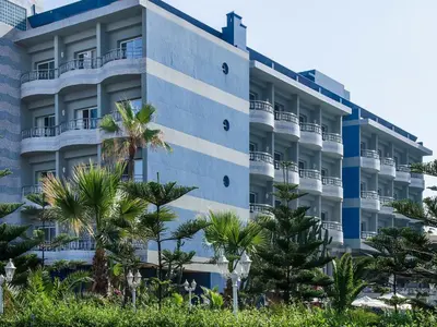 an apartment building with palm trees in front of it at Hôtel Club Val d'Anfa Casablanca Ocean view in Casablanca