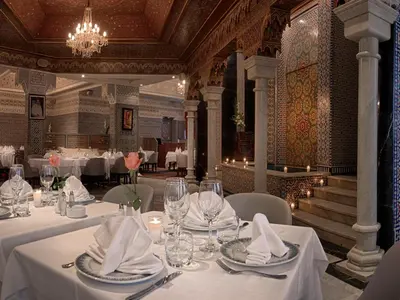 a restaurant with white tables and chairs and a chandelier at Hôtel Club Val d'Anfa Casablanca Ocean view in Casablanca