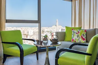 a living room with green chairs and a table and a window at Barceló Casablanca in Casablanca
