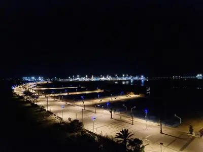 a parking lot with street lights at night at luxe appartement met zeezicht en zwembad Mohammedia Parc in Mohammedia