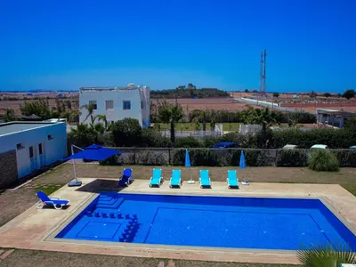 a swimming pool with chairs and umbrellas at Instant Saisons - Ferme d'hôtes in Skhirat