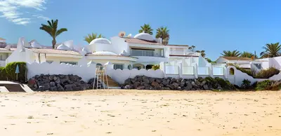 a white house on the beach with palm trees at L' Amphitrite Palace Beach Resort & Spa in Skhirat