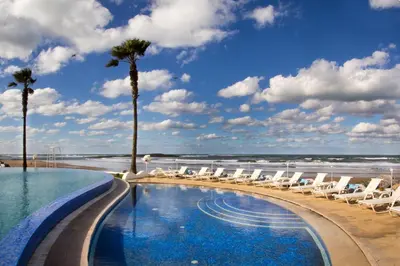 a swimming pool with chairs and the beach at L' Amphitrite Palace Beach Resort & Spa in Skhirat