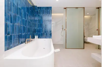 a bathroom with a tub and a shower with blue tiles at Royal Hideaway Casablanca in Casablanca