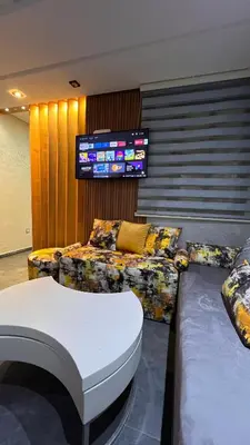 a living room with a couch and a tv at Résidence Galets Sur Mer in Dar Bouazza