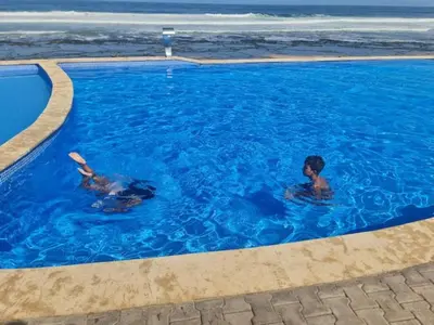 two people swimming in a swimming pool near the ocean at Océan Beach in Tamaris