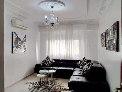 a living room with a black leather couch and a chandelier at Splendid appartament a 3 Min de la mer et de la mosquée hassan 2 in Casablanca