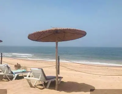 two chairs and an umbrella on a beach at Deluxe apartments in Casablanca