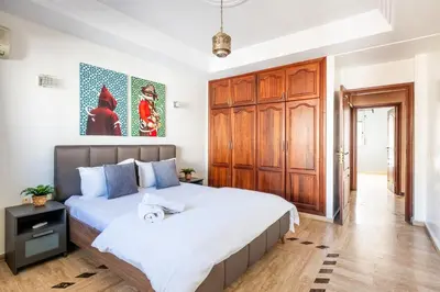 a bedroom with a large bed and a wooden closet at Arribat Center Mall- TT Holidays Agdal in Rabat