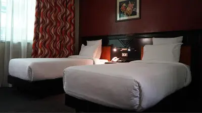 two beds in a hotel room with white sheets at Hotel Toubkal in Casablanca
