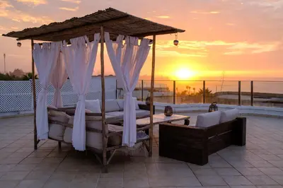 a bedroom with a canopy bed with a sunset in the background at Sunset escape by the sea in Temara