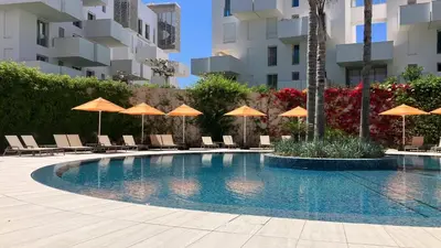 a swimming pool with chairs and umbrellas at Casablanca Appartement haut standing CFC in Casablanca