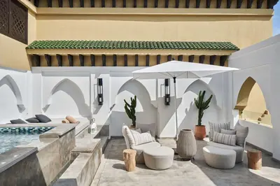 an outdoor patio with a pool and chairs and an umbrella at Mazagan Beach & Golf Resort in El Jadida
