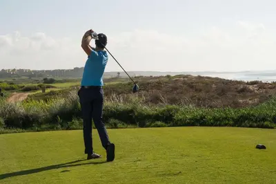 a man swinging a golf club on a golf course at Mazagan Beach & Golf Resort in El Jadida