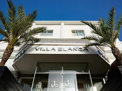 a white building with palm trees in front of it at Villa Blanca Urban Hotel in Casablanca