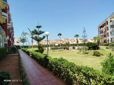 a walkway next to a park with palm trees and buildings at appartement au bord de l'eau in Mohammedia
