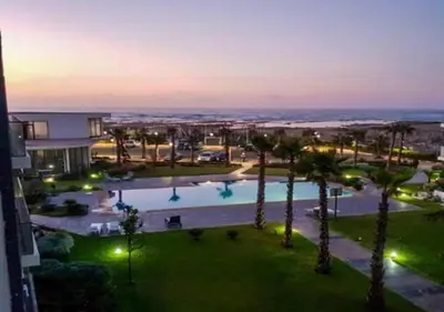a view of a pool with palm trees and a building at Garden Bay - Appartement en bord de mer in Tamaris