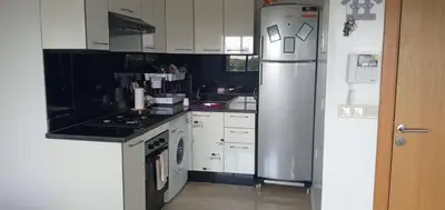 a kitchen with white cabinets and a stainless steel refrigerator at Garden Bay - Appartement en bord de mer in Tamaris