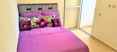 a bed with pink sheets and pillows on it at joli appartement près de la mer in Casablanca