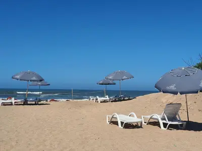 a beach with chairs and umbrellas and the ocean at HEAVEN BEACH in Sidi Rahal