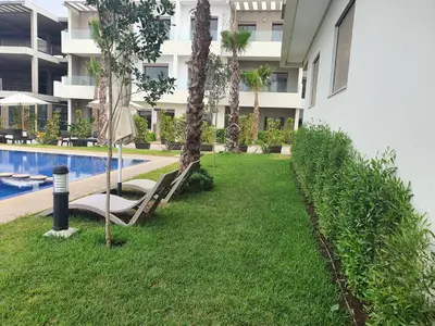 a resort yard with a pool and palm trees at HEAVEN BEACH in Sidi Rahal
