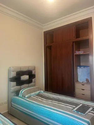 a bed in a room with a wooden cabinet at Appartement avec piscine proche de la plage in Mohammedia