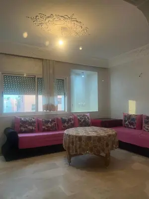 a living room with a pink couch and a table at Appartement avec piscine proche de la plage in Mohammedia