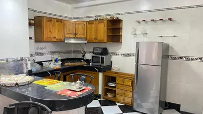 a kitchen with wooden cabinets and a stainless steel refrigerator at Housse F2 famille in Rabat
