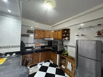 a kitchen with wooden cabinets and a refrigerator at Housse F2 famille in Rabat