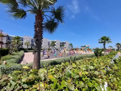 a palm tree in a park with a playground at BLANCA BEACH Sidi Rahal Front Mer in Sidi Rahal